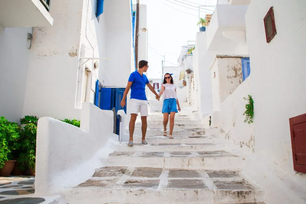 Familieferie i Europa. Lykkelig par på gaten i en typisk tradisjonell gresk landsby på øya Mykonos i Hellas.