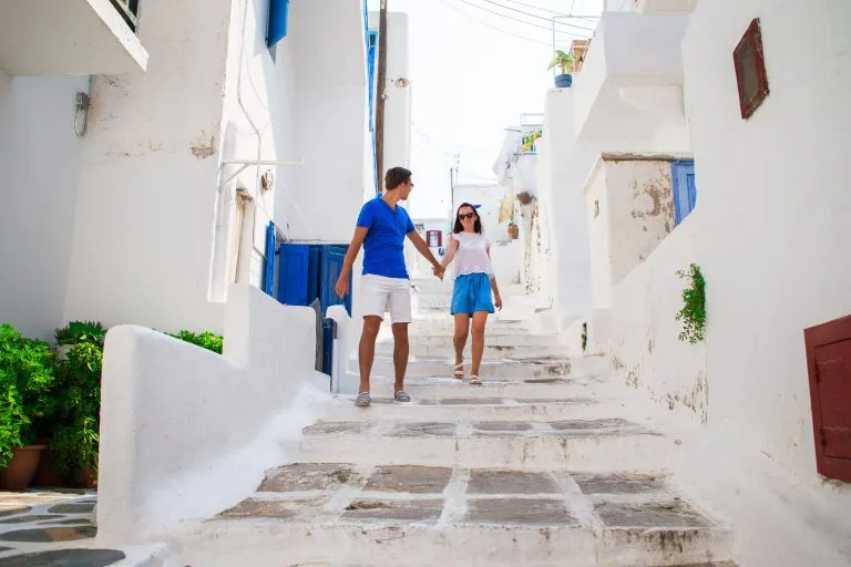 Perheloma Euroopassa. Onnellinen pariskunta tyypillisen kreikkalaisen perinteisen kylän kadulla Mykonoksen saarella Kreikassa.