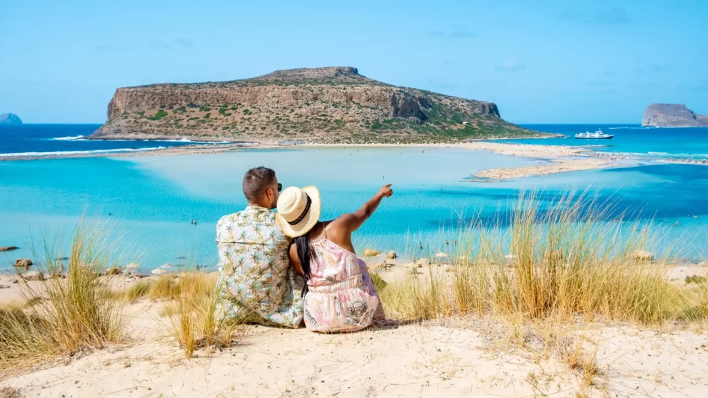 Kreta, Hellas, Balos-lagunen på øya Kreta, Hellas. Turister slapper av ved det krystallklare havet på Balos-stranden. Et par menn og en kvinne besøker stranden på en solskinnsdag under en ferie i Hellas.