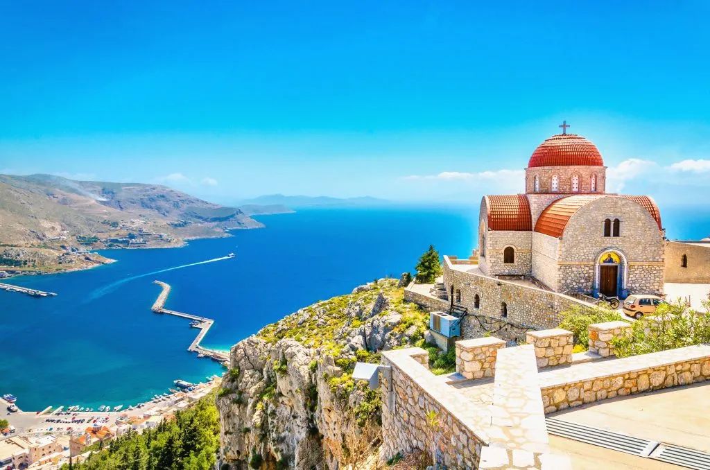 Avlägsnad kyrka med rött tak på klippa, Grekland