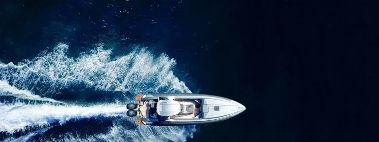 Ultrabrede luftfoto med drone, ovenfra og ned, av en luksuriøs, oppblåsbar hurtigbåt som kjører i høy hastighet i Egeerhavets dypblå hav i Hellas.